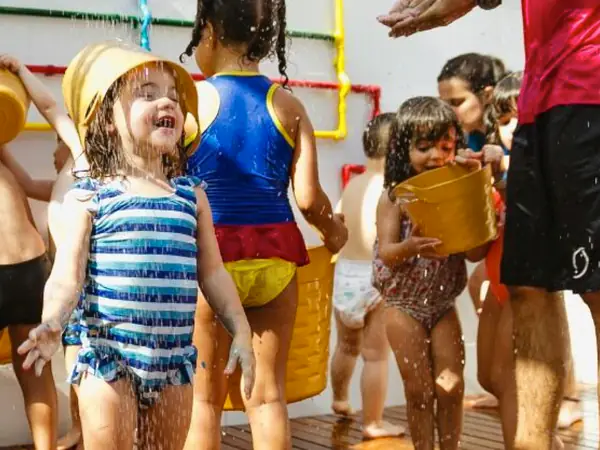 Crianças de roupa de banho brincando com baldes de água em uma festa na Fábrica