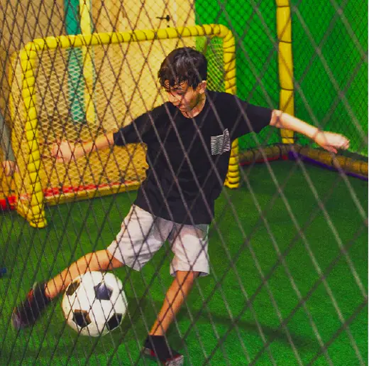Menino chutando a bola no campinho de futebol da Fábrica